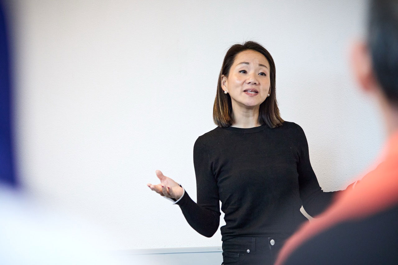 Jenny Kan in a blue suit, arms folded, at a product workshop